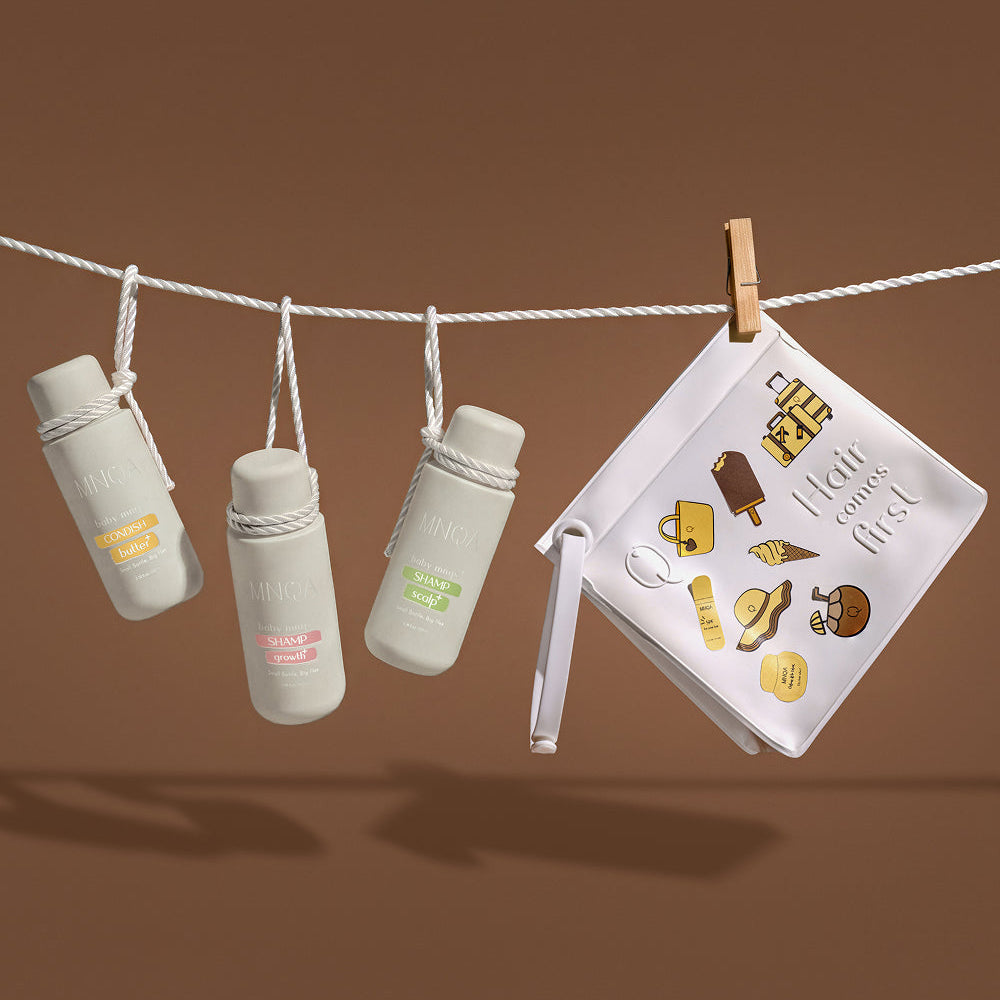 A styled product shot featuring four miniature white insulated bottles hanging from a white clothesline, with a small white pouch clipped to the right by a wooden clothespin against a solid brown background.